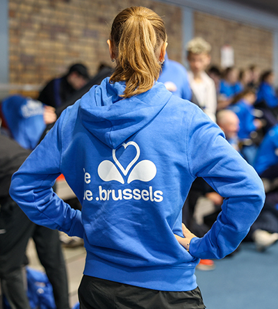 Une jeune sportive debout de dos, portant un pull aux couleurs de la Région bruxelloise