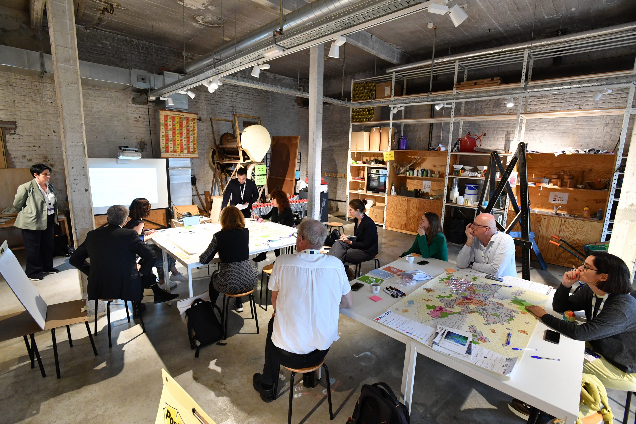 Mensen zitten rond tafels tijdens een atelier.