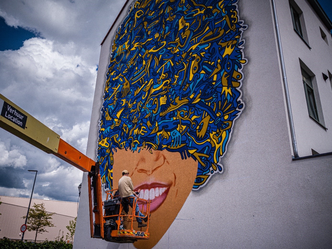 A mural depicting a woman with a hat full of blue and yellow objects.