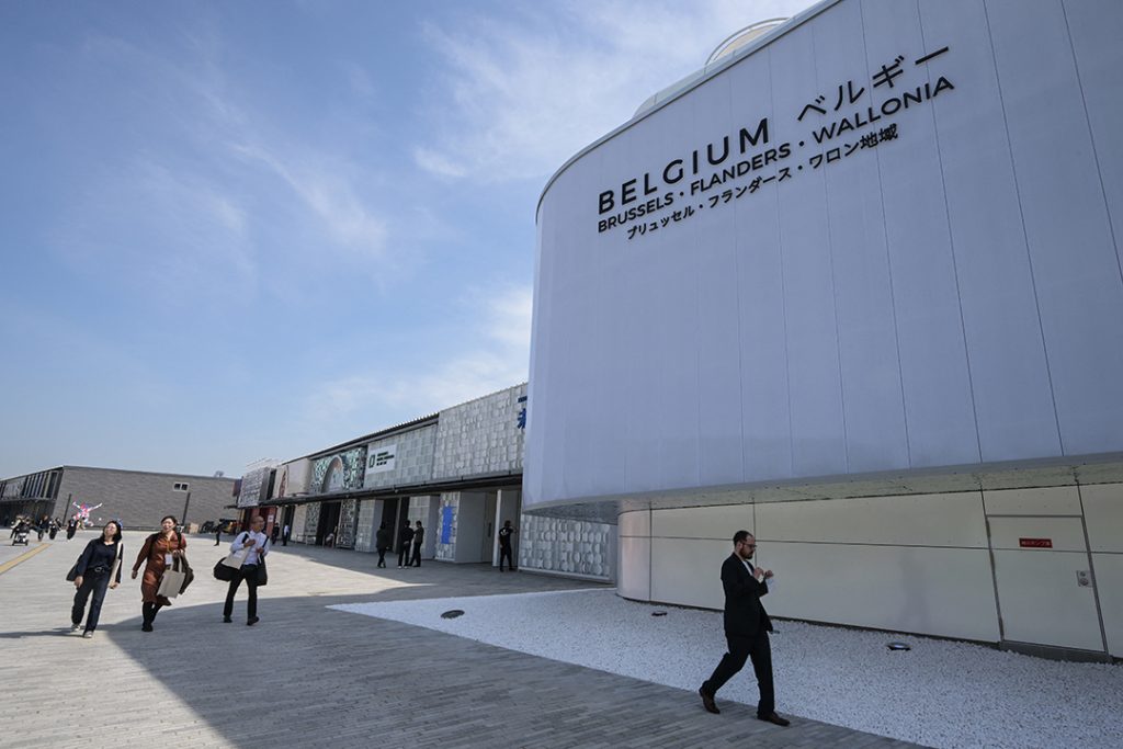 Des visiteurs longent le pavillon belge de l'Expo 2025 Osaka, sous un ciel bleu.