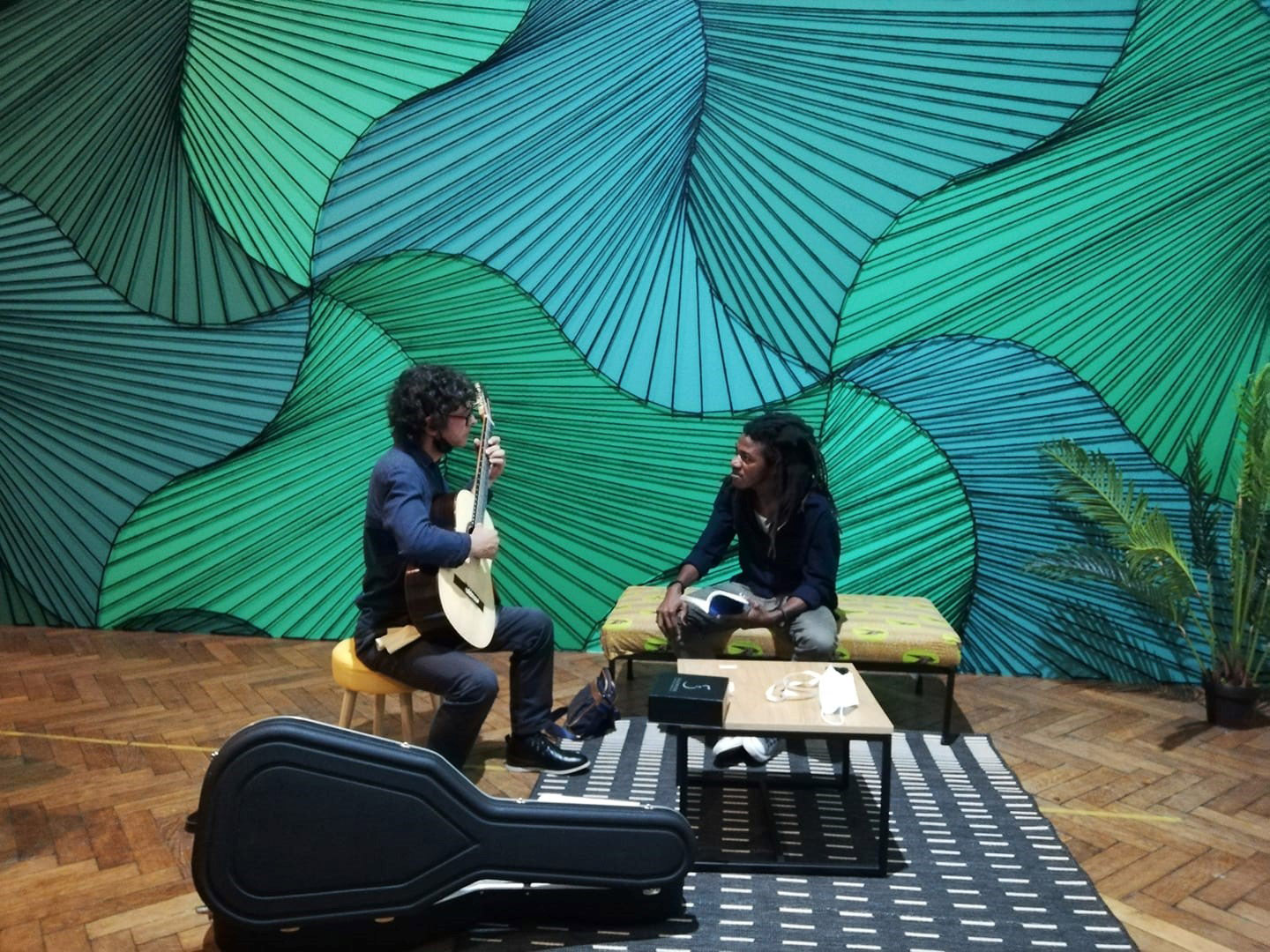 the poet and the guitarist seated and facing each other during their performance