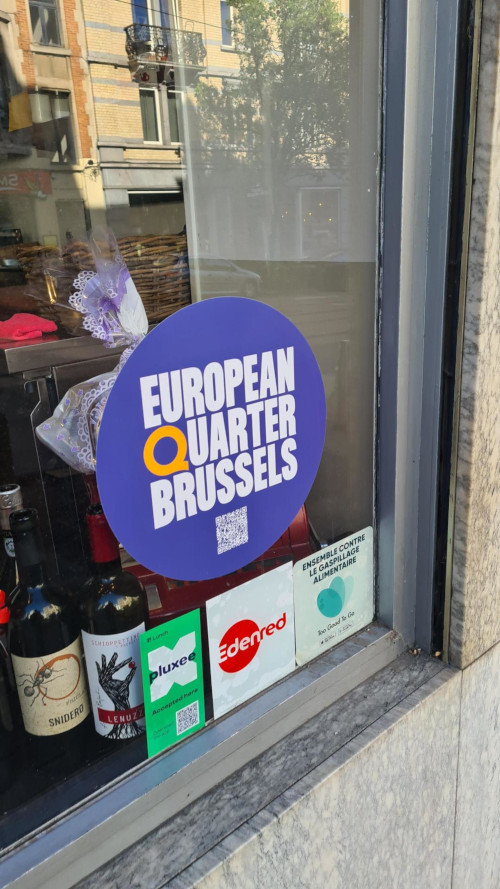 A round blue sticker with the new logo of the European Quarter in a shop window.