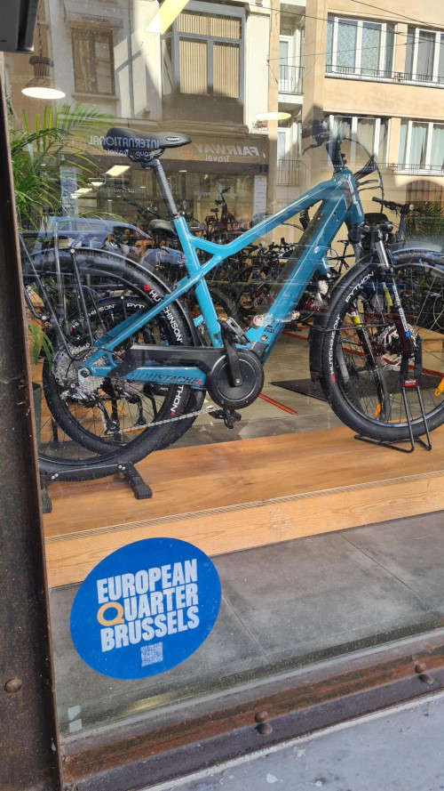 Een blauwe ronde sticker met het nieuwe logo van de Europese wijk in een etalage.