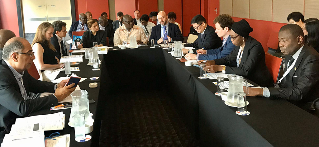 De deelnemers vergaderen zittend rond een tafel.