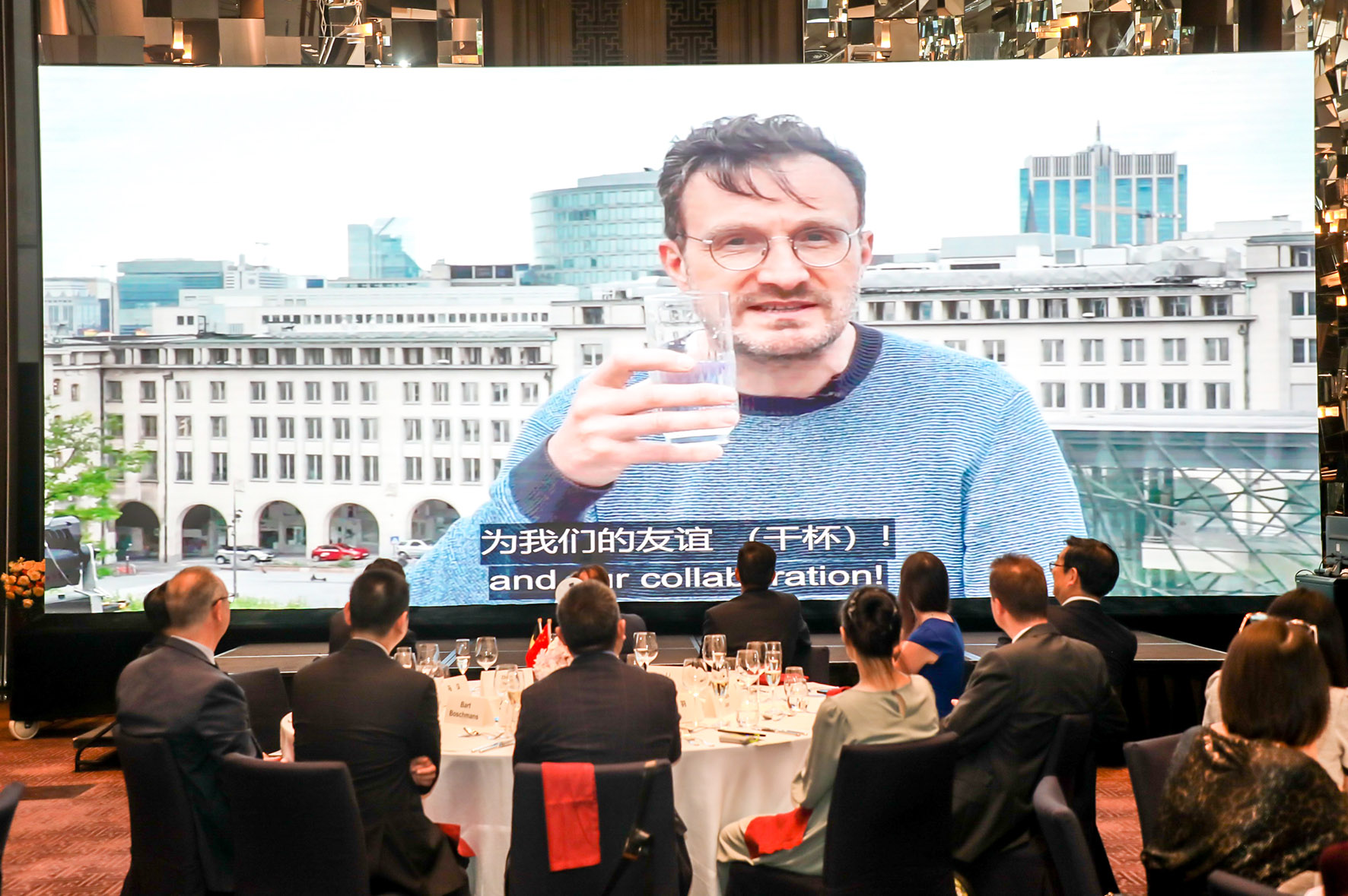 Video of P. Smet raising his glass, with a view of Brussels in the background