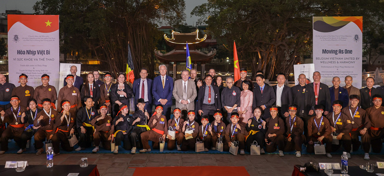 The Brussels delegation and martial arts practitioners stand and kneel in front of the temple.