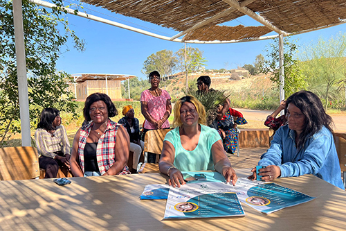 Managers and beneficiaries of the project, seated under a straw canopy